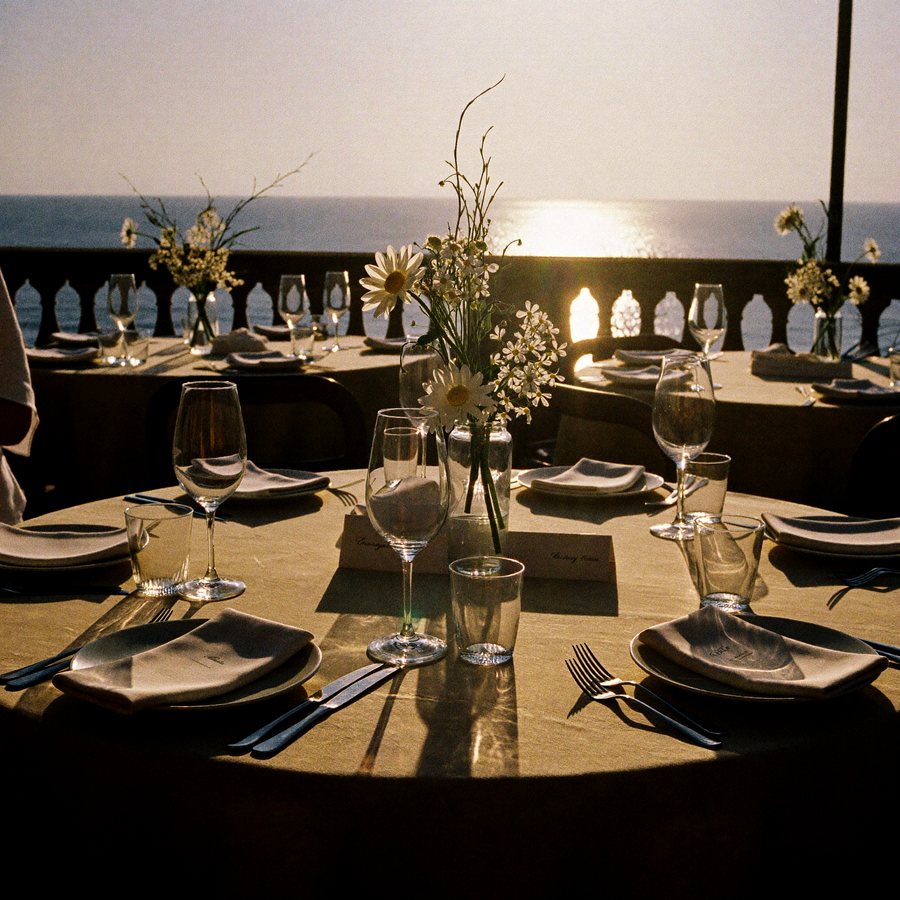 A sunlit terrace set with glassware above the sea.