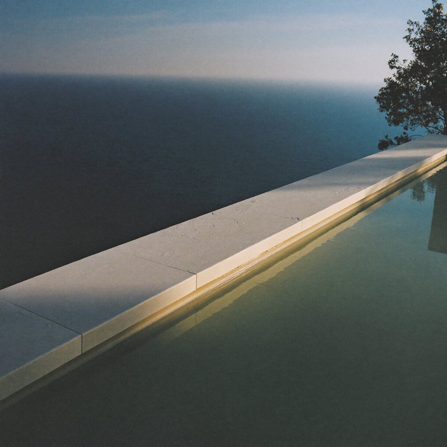 A villa pool edge meeting the sea at dawn.