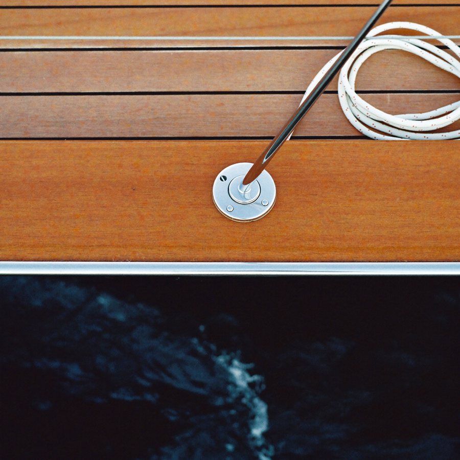 A teak side deck and chrome cleat, water rushing past.