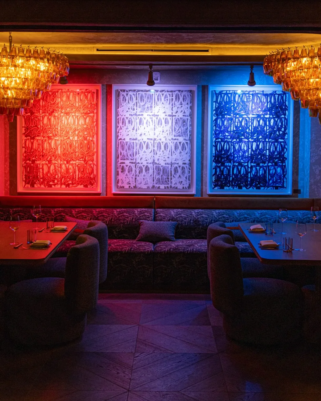 The dining room at Harbour Club: banquettes under three lit panels.