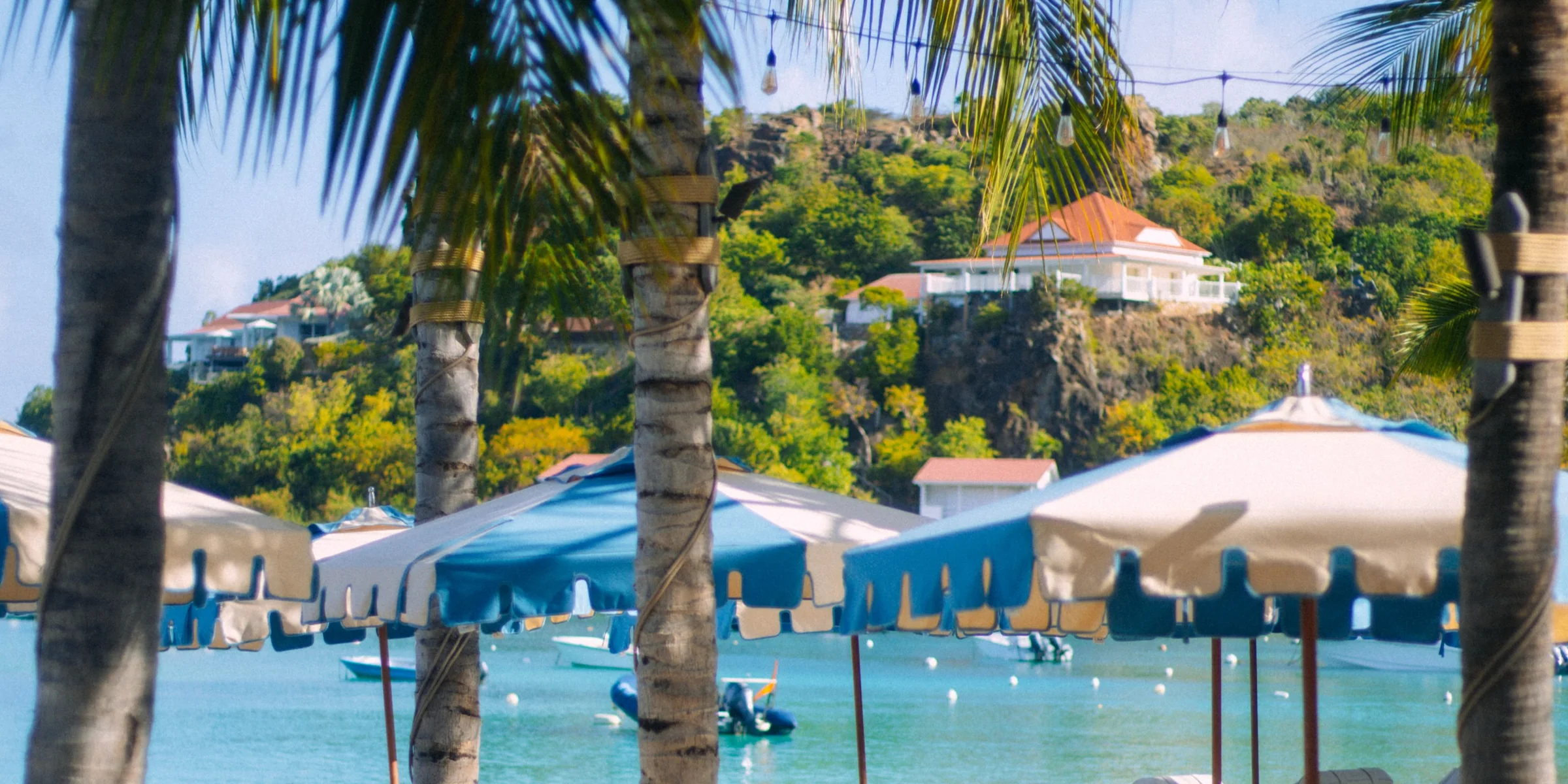 Blue parasols and loungers under the palms at La Guérite Beach, Saint-Jean.