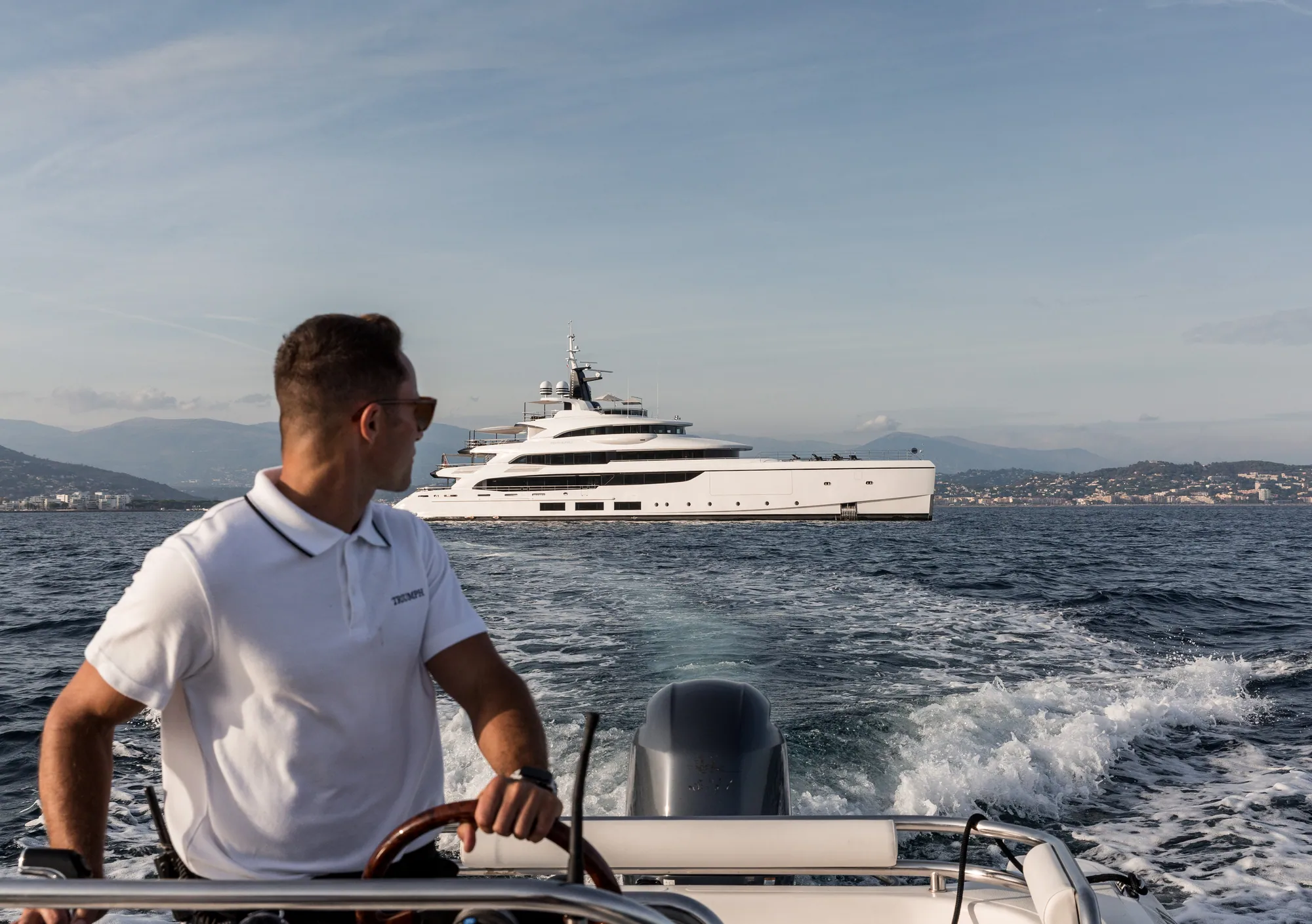 At the helm of the tender, TRIUMPH behind.